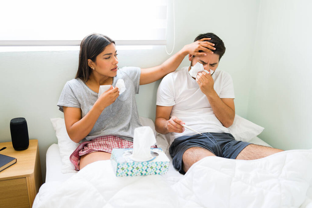 Onko sinulla kuumetta? Rakastava tyttöystävä koskettaa poikaystävänsä otsa tuntea hänen lämpötilansa, kun sairas huono flunssa - Valokuva, kuva