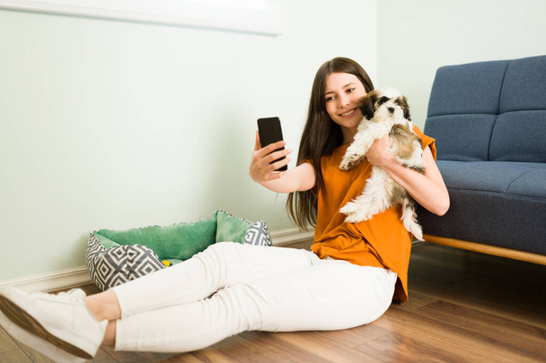 ¡Tengo un cachorro nuevo! Emocionada mujer caucásica tomando una selfie con su hermoso perro shih tzu para publicar la foto en sus redes sociales - Foto, Imagen