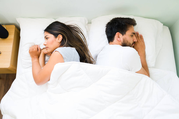 Κάτοψη ενός ελκυστικού ζευγαριού που γυρίζει την πλάτη του και νιώθει θυμό ο ένας με τον άλλο μετά από καυγά πριν τον ύπνο - Φωτογραφία, εικόνα