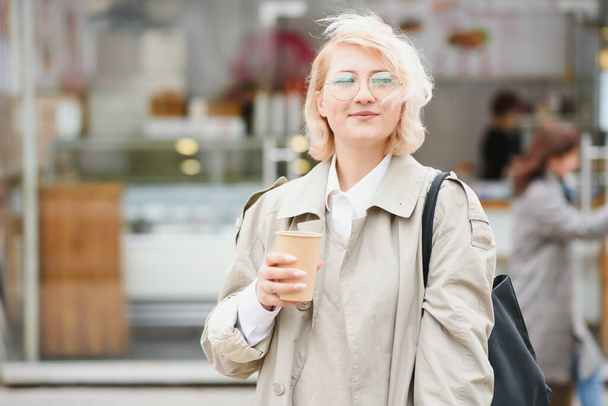 Cheerful woman in the street drinking morning coffee in sunshine light - Foto, Imagen