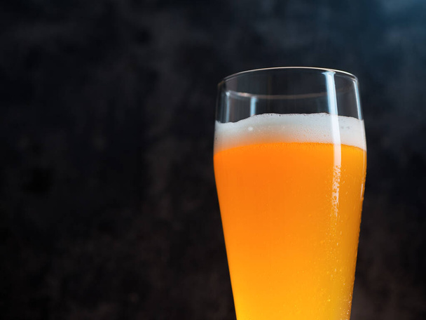 Стакан пшеничного пива на темном фоне крупным планом с копирайтом - Фото, изображение