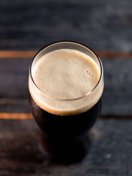 Vista superior de un vaso de cerveza de portero en una mesa oscura del pub - Foto, Imagen
