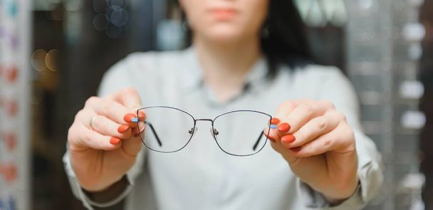 Closeup of optometrist, optician giving glasses to try - 写真・画像