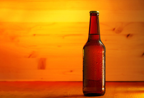 Een fles koud licht bier op een houten tafel, kopieer ruimte - Foto, afbeelding