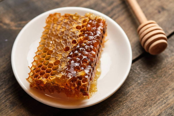 Primo piano a nido d'ape. Miele fresco dal campo e bastone di miele su un vecchio tavolo di legno. - Foto, immagini