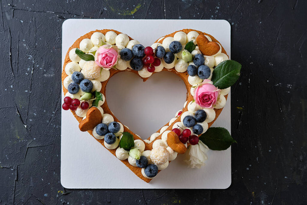 Honey cake with fresh blueberries, herbs and cream cheese cream. Dessert for a loved one. Heart cake. - Foto, afbeelding