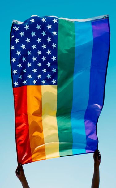 qualcuno sventola una bandiera degli Stati Uniti arcobaleno sul cielo blu - Foto, immagini