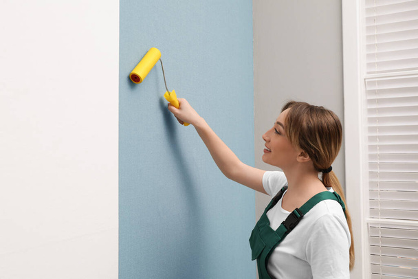Worker hanging stylish wall paper sheet indoors - Фото, изображение