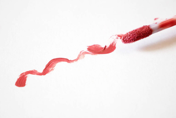 Υγρό κραγιόν σε λευκό φόντο, κόκκινο υγρό κραγιόν με ένα μόνο χρώμα swipe, closeup - Φωτογραφία, εικόνα