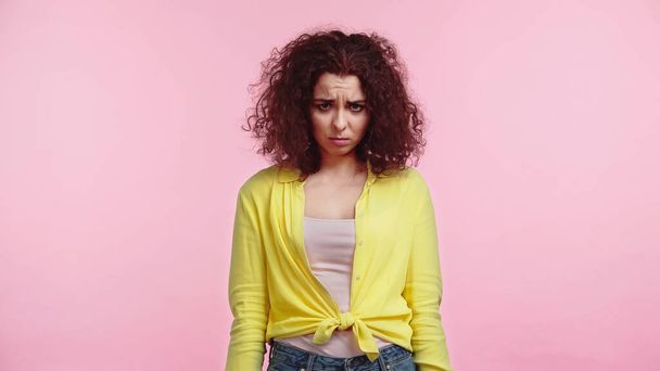 offended and curly woman standing isolated on pink  - Fotoğraf, Görsel