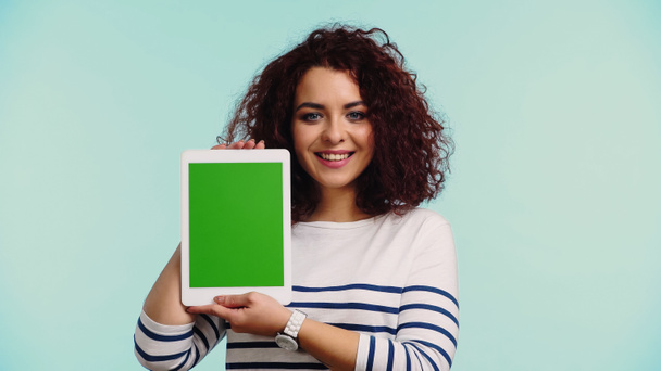 happy young woman holding digital tablet with green screen isolated on blue  - Foto, Imagen