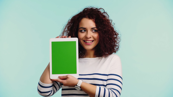 allegra giovane donna in possesso di tablet digitale con schermo verde isolato su blu  - Foto, immagini