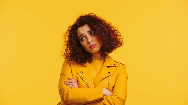upset young woman in leather jacket standing with crossed arms isolated on yellow - Fotografie, Obrázek