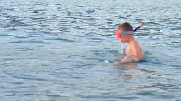 Kleiner Junge schnorchelt bei Sonnenuntergang im Meer nahe der Küste - Filmmaterial, Video