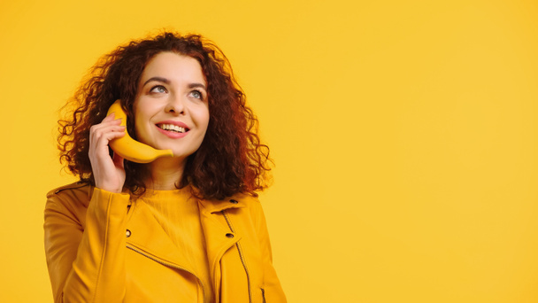 happy woman imitating phone conversation with banana isolated on yellow - Photo, Image