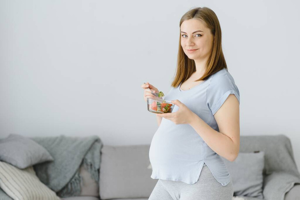 Beautiful healthy pregnant woman eating vegetable salad - Foto, afbeelding