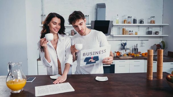 young man showing article in business newspaper to sexy woman in unbuttoned shirt - Photo, Image