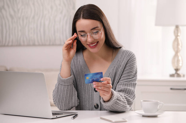 Mujer con tarjeta de crédito utilizando el portátil para las compras en línea en la mesa blanca en el interior - Foto, imagen