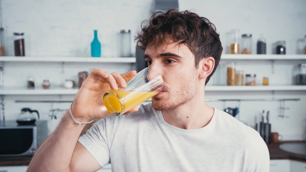 man in wit t-shirt drinken verfrissend sinaasappelsap in de ochtend - Foto, afbeelding