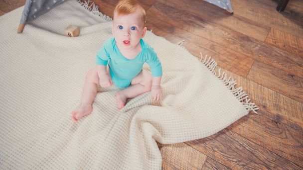 high angle view of infant boy sitting on blanket and looking at camera - 写真・画像
