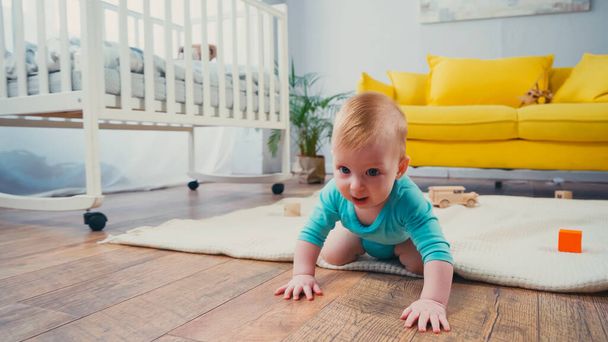 Säugling krabbelt im Wohnzimmer auf dem Boden  - Foto, Bild