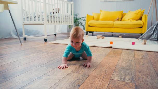 infant boy in blue romper crawling on floor in living room  - Foto, Bild