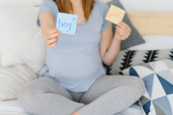 Pregnant woman with a sticky note and writing love boy or girl on sticky note and add on her belly,Pregnant Concept,Selective Focus - Foto, imagen