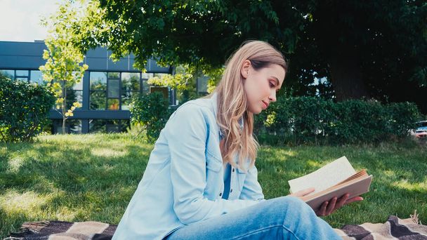 side view of young woman reading book in park - 写真・画像