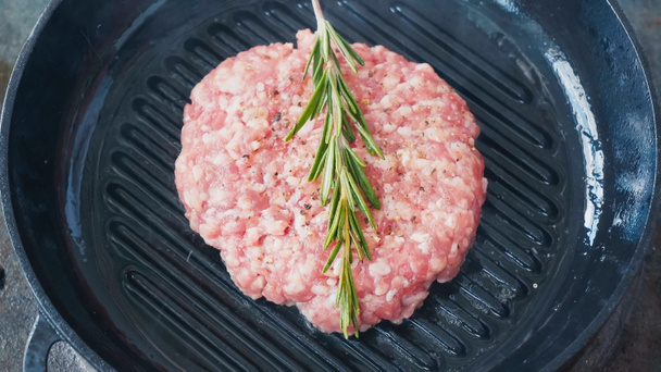 high angle view of mince patty with salt and rosemary branch on hot pan - Photo, Image