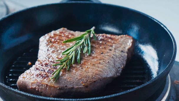 close up of fresh rosemary branch on beef steak  - Foto, afbeelding
