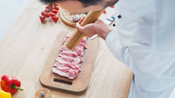 vista parcial del chef con sazón de molino de sal en rodajas lomo de ternera  - Foto, Imagen