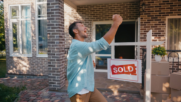 excited man rejoicing near sold board and new house - Photo, Image