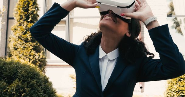 Happy african american businesswoman using vr headset outside - Foto, Imagem