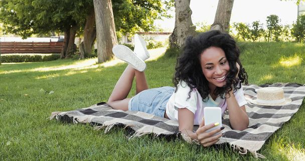 joyeuse femme afro-américaine prenant selfie dans le parc  - Photo, image