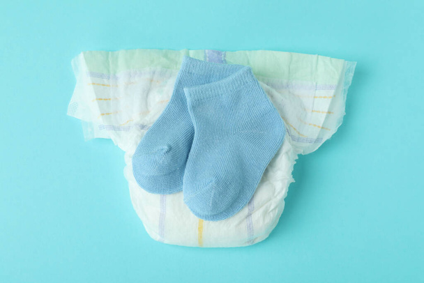 Diaper with baby socks on blue background - Foto, immagini