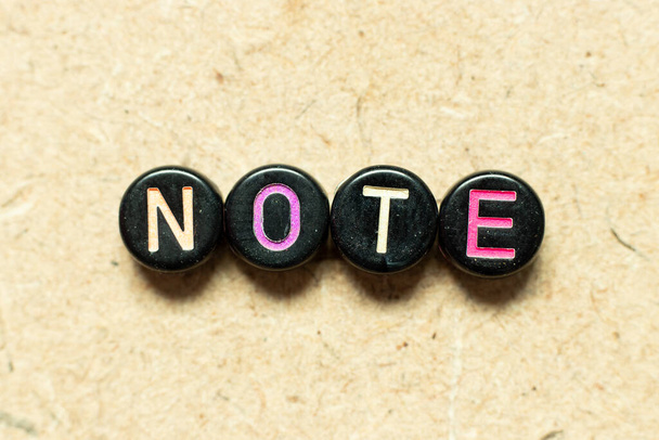 Color negro redondo alfabeto letra bloque en nota de palabra sobre fondo de madera - Foto, imagen