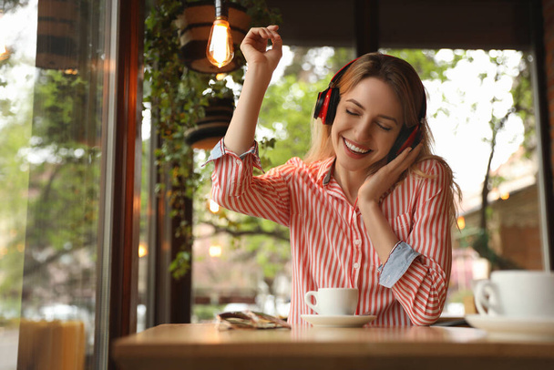 Young woman with headphones listening to music in cafe - Fotografie, Obrázek