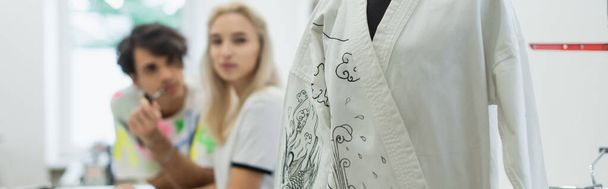 enfoque selectivo de kimono con dibujo tradicional cerca de diseñadores borrosos en atelier, bandera - Foto, Imagen