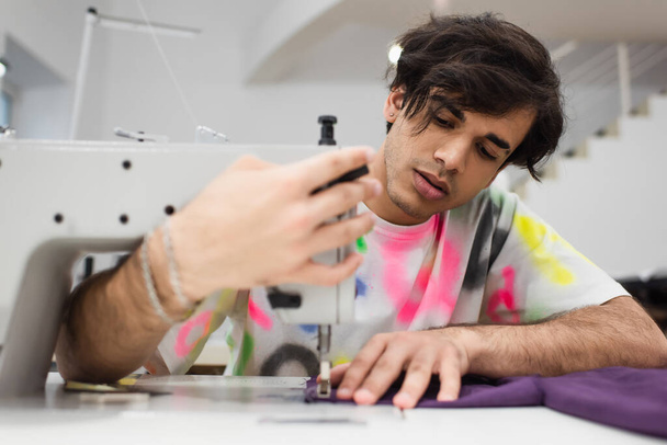 модный портной регулировки швейной машины во время работы в ателье - Фото, изображение