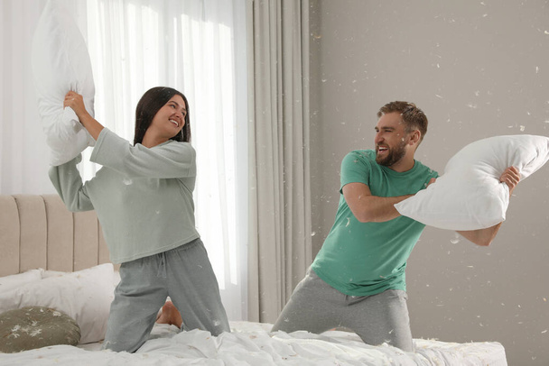 Счастливая молодая пара веселится битва подушками в спальне - Фото, изображение