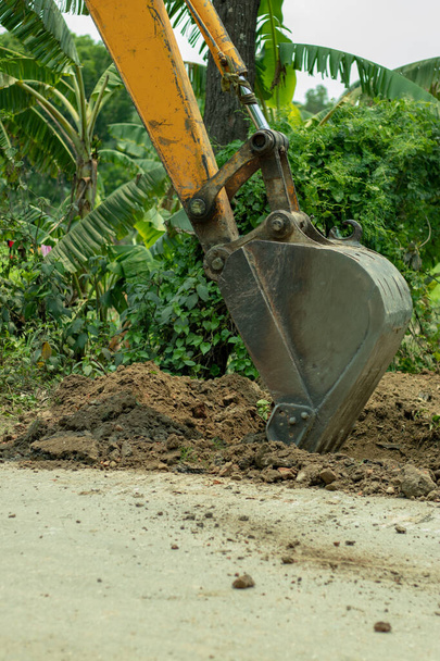 L'escavatore che lavora sulla strada in costruzione e lavora con un operaio - Foto, immagini