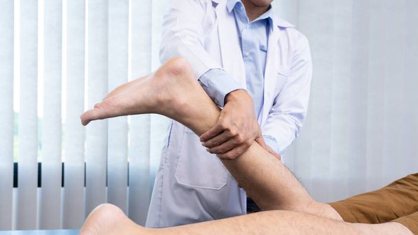 Lékařský koncept mužský lékař diagnostikování mužské nohy tím, že stiskne nohu, protože hraje fotbal. - Fotografie, Obrázek