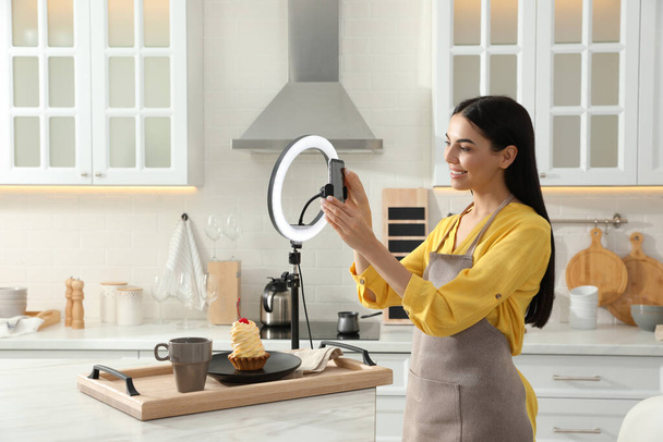 Blogger preparing for video recording in kitchen at home. Using smartphone and ring lamp - Fotoğraf, Görsel