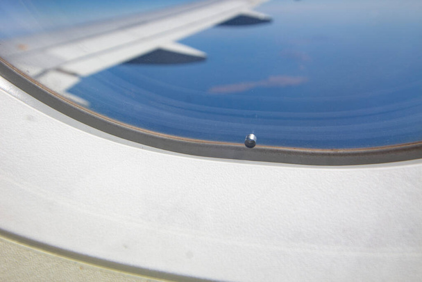 Loch im Fenster des Flugzeugs. Bild schließen. - Foto, Bild