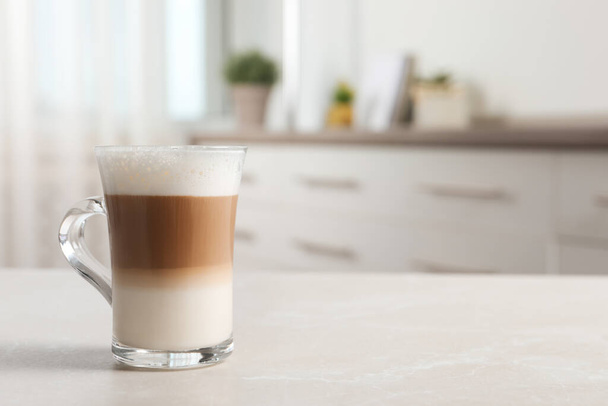 Glass cup of delicious layered coffee on light marble table indoors, space for text - Fotografie, Obrázek