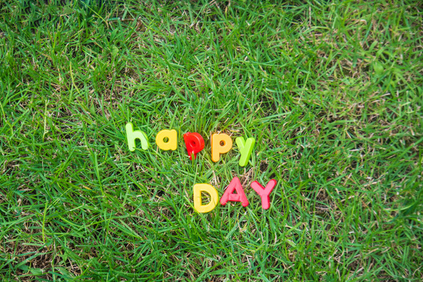 Happy Day Schriftzug mit Spielzeugbuchstaben auf dem Gras im Garten des Hauses geschrieben - Foto, Bild