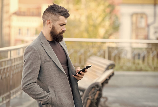Llegar a la gente sobre la marcha con el marketing de SMS. Hombre barbudo leer sms urbano al aire libre. Mensajería de texto. Dispositivo móvil. Nueva tecnología. La vida moderna. Comunicación empresarial - Foto, imagen