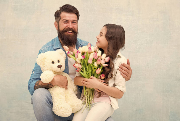 daughter and father celebrate birthday. girl greeting dad with fathers day. happy family portrait with teddy bear. spring flower bouquet. womens day. prepare tulips for mothers day - Fotó, kép