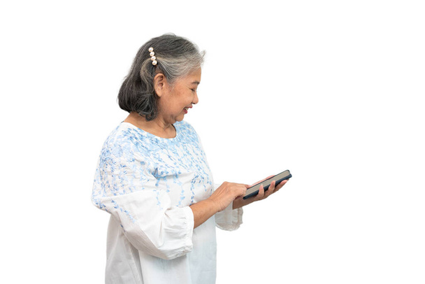 Happy Asian senior woman holding smartphone and using online apps in mobile phone and texting sms message chatting on isolated background, A könnyen használható és az alkalmazás koncepciója idősek számára. - Fotó, kép