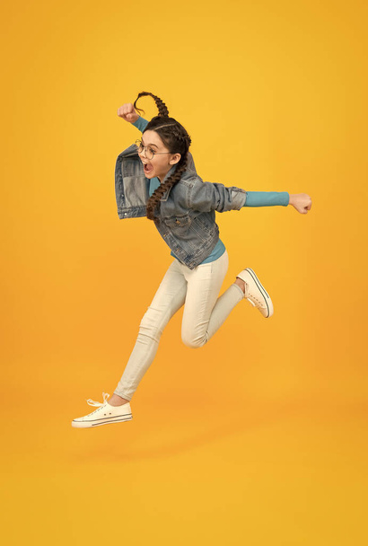 fly so high. kid having real fun. success in sport. happy winner child. teen girl jump on yellow background. This is a complete triumph. run to success. concept of childhood happiness - Foto, afbeelding